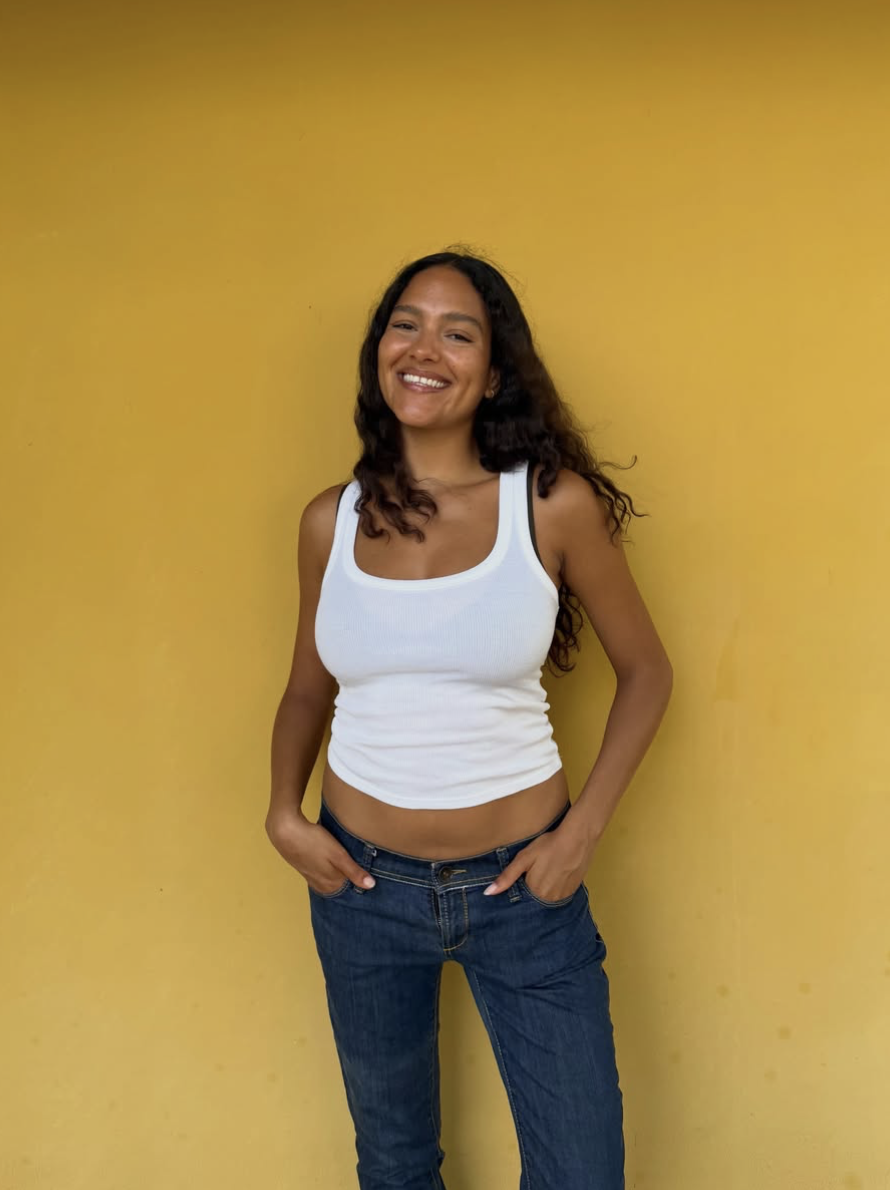Joline smiling against a yellow wall
